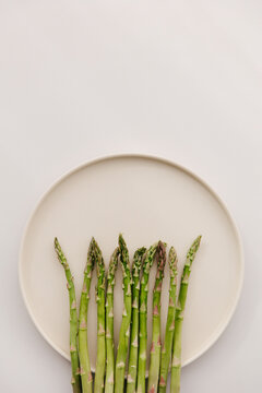 Several green asparagus on a beige plate.
