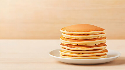 Delicious golden pancakes stacked on a plate, on a wooden table, perfect for breakfast menus or food blogs.