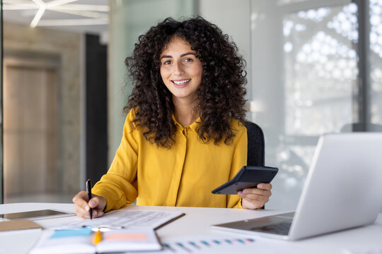 Paperwork, businesswoman writing data in spreadsheet and filling out tax forms, woman inside office using laptop, financier accountant preparing financial investment report, smiling looking camera
