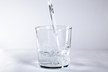 Glass tumbler filling with a glass of water on a white background. Concept: Drink, water, glass of water.