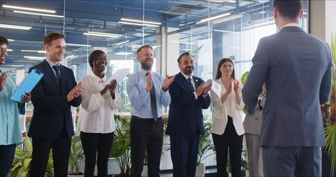 Professional business team celebrating success. Group of happy diverse multiracial people applauding their leader after his inspiring presentation in a corporate meeting