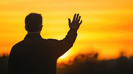 Fototapeta premium Silhouette of a middle-aged man waving goodbye at sunrise against a vibrant orange sky with expansive copyspace for text in the background