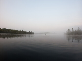 Solo kayak paddling in a misty morning on the lake in the Boundary Waters (BWCA)