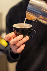 Male hands of a barista making coffee and latte art. The process of making coffee.