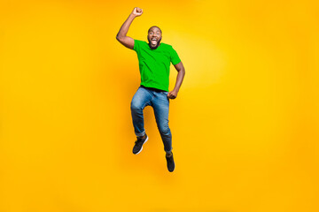 Obraz premium Full length body size photo of jumping man wearing red t-shirt jeans denim rejoicing with his victory at something while isolated with yellow background