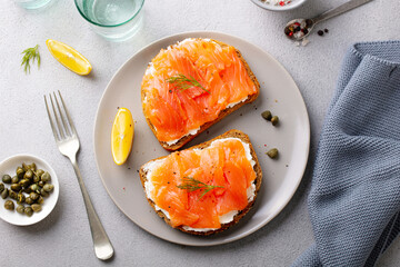 Sandwich, toast with smoked salmon and cream cheese on plate. Grey background. Close up. Top view.