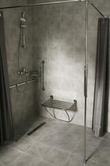 Modern accessible bathroom with grab bars, a wall-mounted shower seat designed for individuals with mobility challenges.