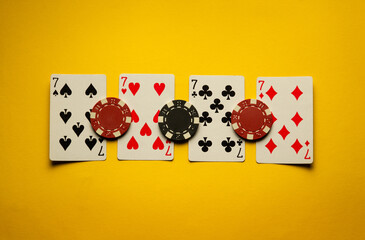 Poker cards with a combination of four of a kind or quads are on a yellow table with chips. The...