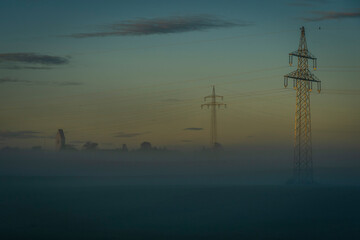 Stromtrasse im trüben Morgennebel auf einem Feld