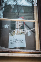 Human skeleton with Welcome sign captured trough window