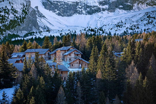 Vall&eacute;e enneig&eacute;e et bois&eacute;e entre au pied d'une montagne avec village de station de ski dans la lumi&egrave;re du jour qui se l&egrave;ve.