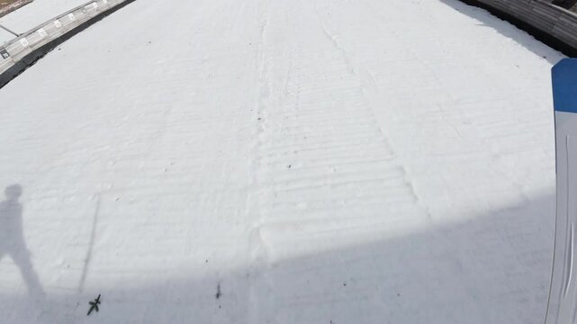 Jumper flying through the air and landing on the snow during hill ski jumping practice, point of view shot. Winter sports experience concept.