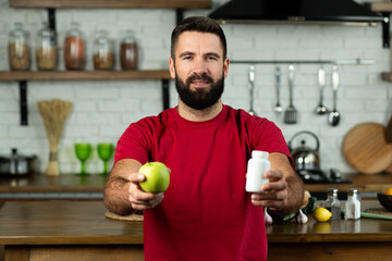 Young man choosing between an apple and bottle of pill, healthy dieting or nutritionist concept