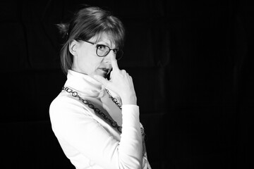 Naklejka premium Frau mit Brille berührt Gesicht als nachdenkliches Schwarzweißporträt