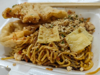 Mie Gacoan, Fried Noodles with Popular Indonesian Spicy Level, served with Fried Dumplings and sprinkled with chicken.