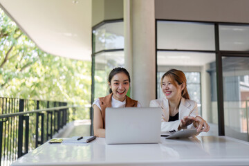 Confident Businesswoman Mentoring New Employee in Modern Office Setting with Laptop and Digital Tablet