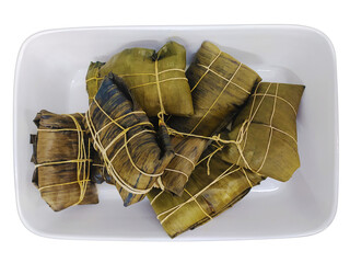 Delicious tamales, meticulously wrapped in banana leaves and tied with twine, rest in a white...