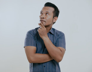 Asian man showing thinking gesture with his eyes looking up isolated on white background.