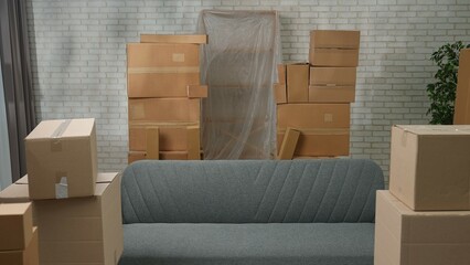 Shot of new apartment, space filled with cardboard boxes and furniture. Interior of new house room with moving stuff in boxes standing in stacks.