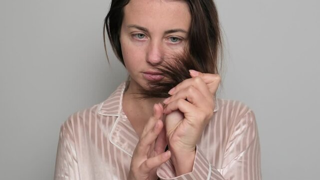 Girl holding her hair with split ends close-up on white background.