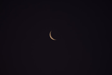 Waxing crescent moon illuminating the dark night sky, casting a soft glow and creating a tranquil, serene atmosphere filled with cosmic beauty and celestial wonder