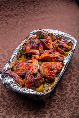 Chicken pieces baked with potatoes in spices on foil