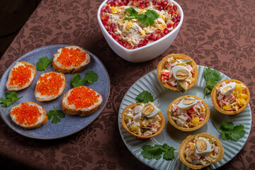 Salad with chicken, pineapple and pomegranate in a heart-shaped salad bowl next to tartlets