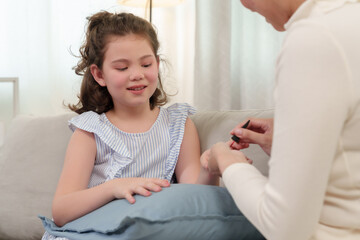 Asian mother and young daughter enjoying playful nail painting session at home. Heartwarming family moment focusing on love, bonding, and creative self-expression in a cozy atmosphere.