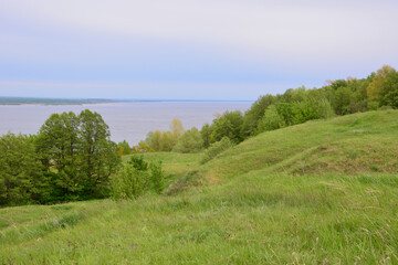 Obraz premium green hills with the river and cloudy sky in the background 