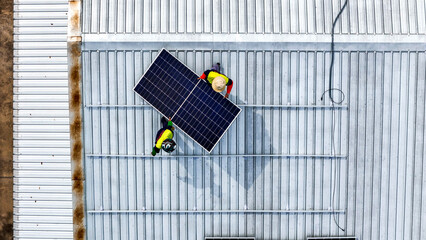 A sustainable energy project featuring solar panels on a roof surrounded by tropical trees,...