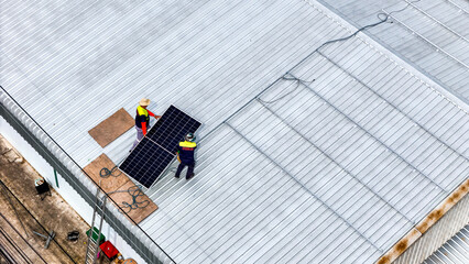 A sustainable energy project featuring solar panels on a roof surrounded by tropical trees,...