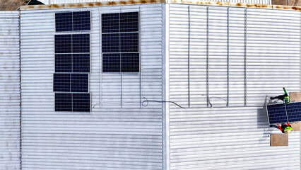 A sustainable energy project featuring solar panels on a roof surrounded by tropical trees,...