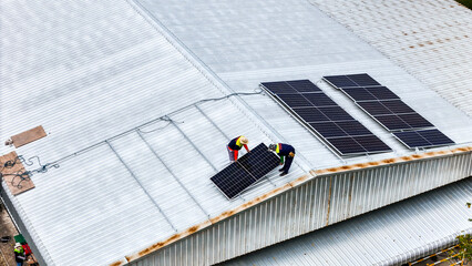 A sustainable energy project featuring solar panels on a roof surrounded by tropical trees,...