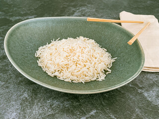 White long rice in oversized pastel green plate in ellipse shape. Chopsticks placed on napkin and over bow. high angle view, close up
