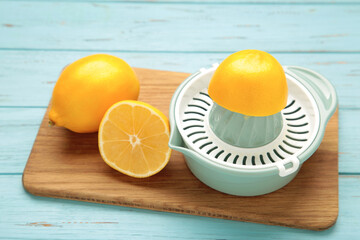 Squeezer and lemons on cutting board on blue wooden background