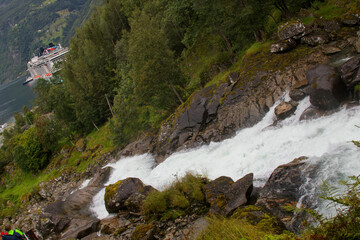 Vigorous water flows over rocks, embraced by lush greenery, creating a serene atmosphere.