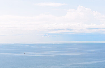 Lone sailboat in the lagoon at Trieste, Italy, on a summer day with white clouds and sky and water in different shades of blue. Nature background