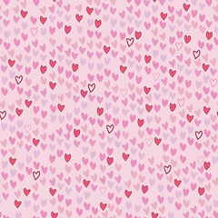 A seamless vector, blending pattern of pink and red hearts irregularly scattered on a light pink background. Great for digital Valentines projects backgrounds, fabrics, or gift wraps.