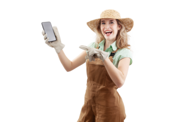 Smiling woman wearing an apron, hat, and gloves for gardening, isolated on white background, points at a smartphone. Online gardening shopping in a web store for the arrival of spring and garden work