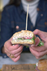 A detailed close-up of a gourmet sandwich being held in both hands. 