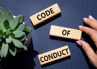 Code of conduct symbol. Wooden blocks with words Code of conduct. Businessman hand. Beautiful deep...