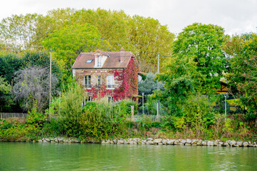 Scenic view of a picturesque brick house surrounded by lush greenery on the banks of the Marne...