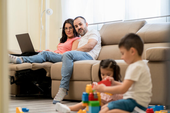 Happy parents watching kids playing with toys