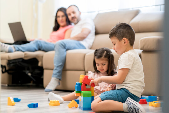 Kids playing with constructor on floor near parents