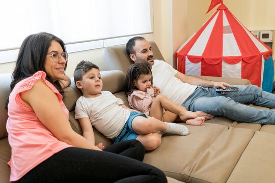 Happy family watching TV in living room with toys