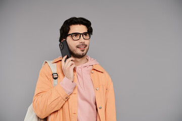 Obraz premium Young man smiling while talking on the phone in a bright urban setting