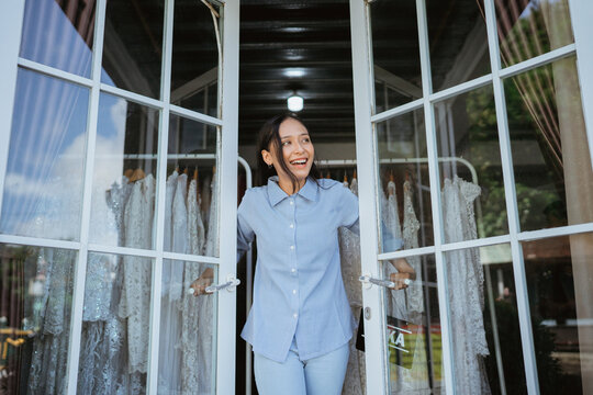 A joyful woman stands confidently at a charming boutique entrance, attracting potential customers