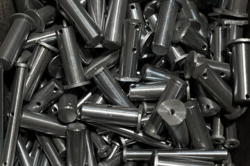 A multitude of shiny metal components sits stacked together in a workshop