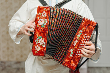 red accordion in hands, close-up view, man in white shirt, national musician instrument