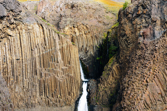 Waterfall with hexagonal basalt columns and rocks.